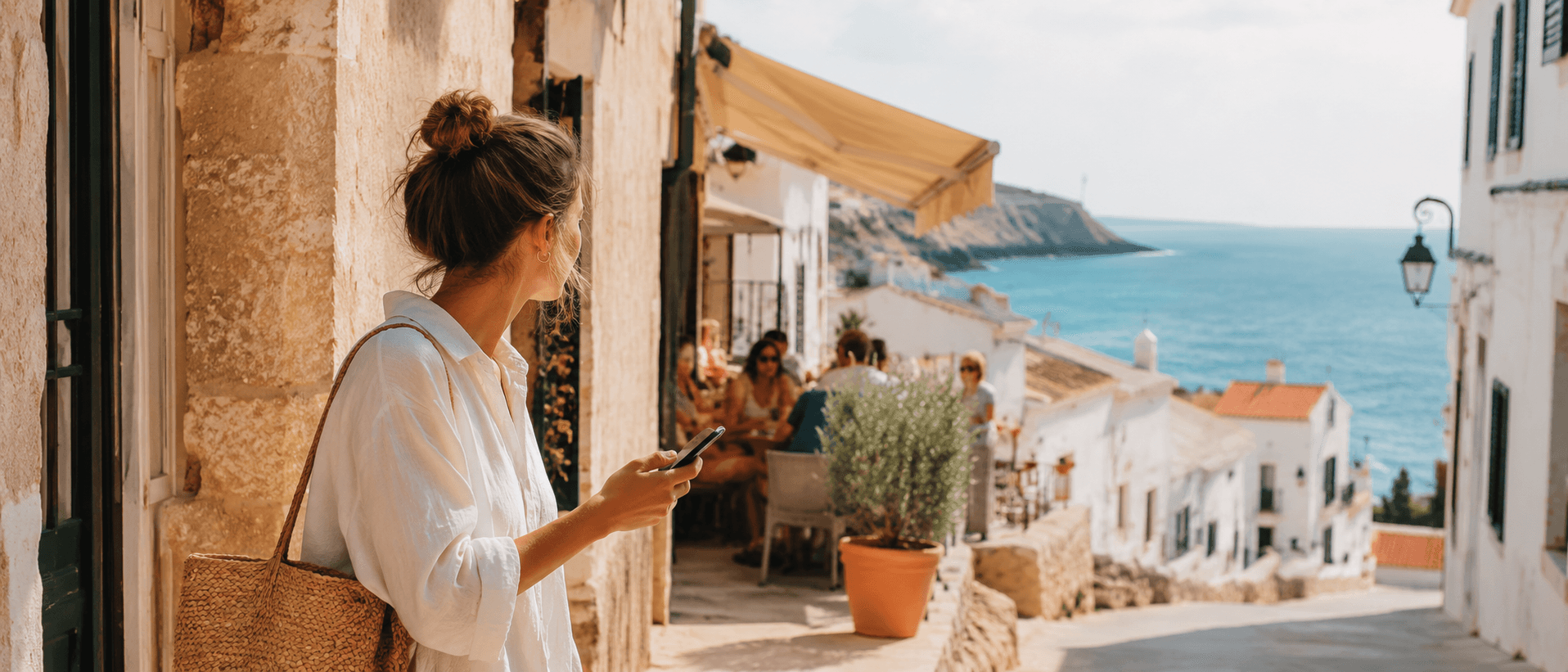 Viajera consultando Awaita en el móvil en una calle de Menorca junto al mar